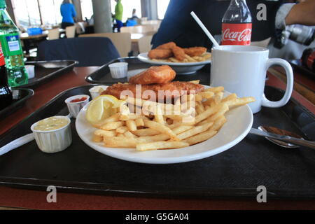 Fish and Chips with lemon, ketchup sauce, chocolate, and Coke with another person Stock Photo