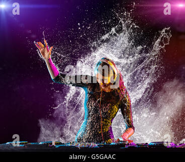Disc jockey brunette girl mixing electronic music and splashing water around Stock Photo
