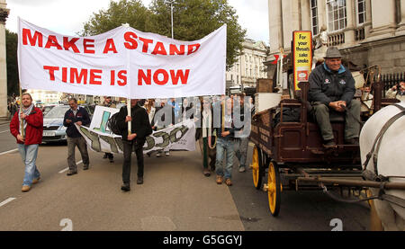 Protestors pass a man with a horse and cart as they make their way to the Central Bank in Dublin, to mark one year since the Occupy Dame Street encampment was started. Stock Photo