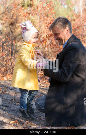Father Helping Little Baby Daughter to Wear Coat Stock Photo