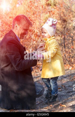 Father Helping Little Baby Daughter to Wear Coat Sun Shining Stock Photo