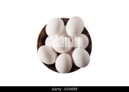 A wooden bowl overhead with white chicken eggs isolated on white. Stock Photo