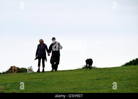 Couple walking with three dogs. Seaford Head, Sussex, England. Stock Photo
