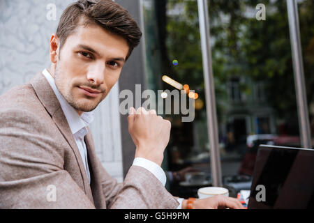 Closeup of serious businessman wearing suit and using modern laptop in coffee shop Stock Photo