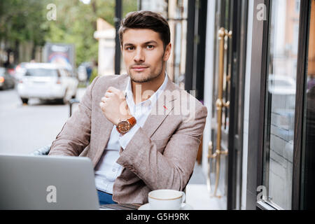 Serious businessman using modern laptop and thinking about something in coffee shop Stock Photo