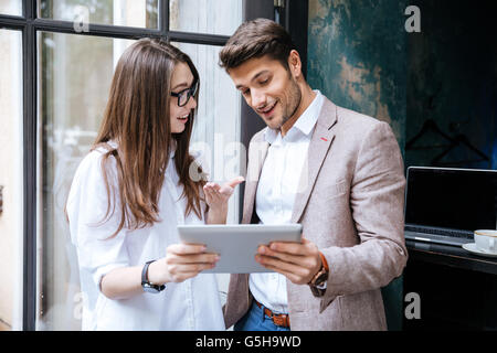 Two young smart businesspeople working on laptop in coffee shop Stock Photo
