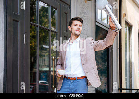 Young handsome businessman greeting someone at coffee shop outdoors
