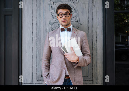 Young fashion man with nerd glasses and stylish hairdo in jacket posing Stock Photo
