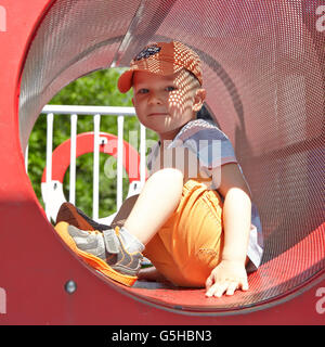 Cute boy playing in tunnel on playground Stock Photo