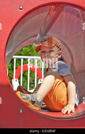 Cute boy playing in tunnel on playground Stock Photo