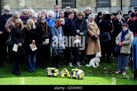 Mourners stand outside church next to a floral tribute left by Sergeant Thursby's children during the funeral service of Sergeant Gareth Thursby at Holy Trinity Church, Skipton. Stock Photo
