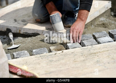 Details with hands of a mason working with cobblestone Stock Photo