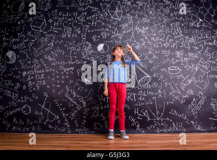 Girl with two braids, big blackboard with mathematical symbols Stock Photo