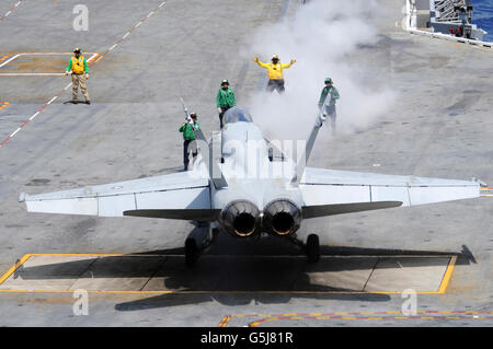 An aircraft director guides an F/A-18 Hornet to the catapult aboard the aircraft carrier USS Carl Vinson. Stock Photo