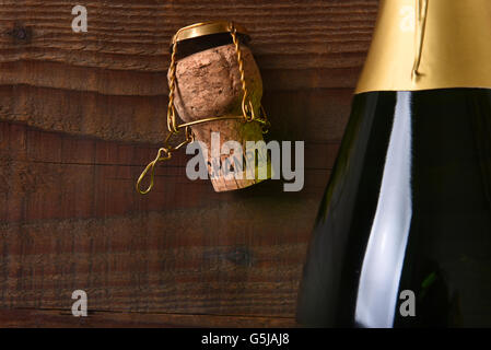 Overhead view of a Champagne bottle next to a cork and cage. Horizontal format on a dark wood background, with copy space. Stock Photo