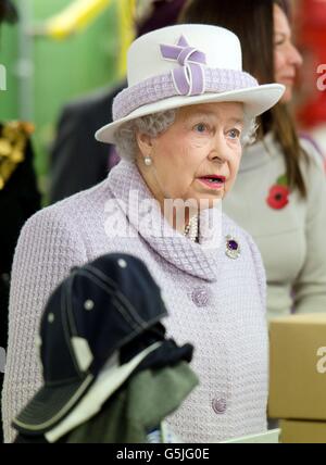 Queen Elizabeth II watches an employee of The Poppy Factory making the red emblem of the British Legion's annual poppy appeal during a visit to the company headquarters in Richmond, London. Stock Photo