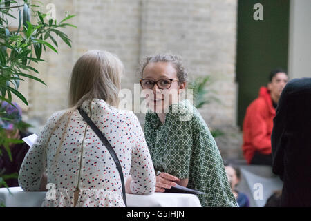 Gathering in classical surrounds, two women talking, man in background Stock Photo