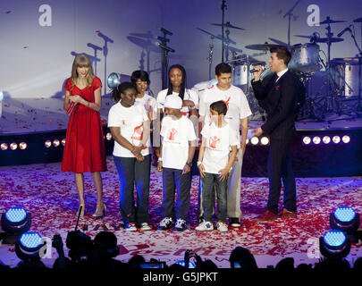 Taylor Swift (left) with with young ambassadors from save the Children - the shopping centre's chosen charity - as she performs at Westfield London Shopping Centre where she turned on the Christmas lights. Stock Photo