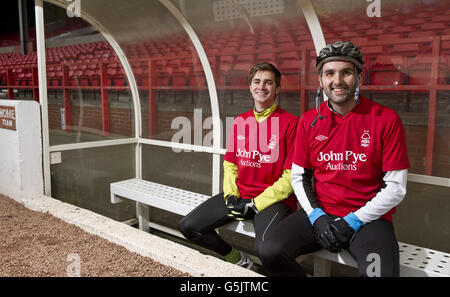 Cyclists Rowan Staszkiewicz and Scott Wilson pose in the dugout before their 26 mile bike ride from The City Ground, Nottingham to the King Power Stadium, Leicester to raise money for Prostate Cancer UK and the Alzheimer's Society. Stock Photo