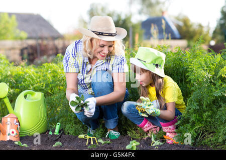 Mother and daughter child planting strawberry seedlings in summer