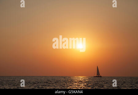 Sailboat sailing on ocean horizon at sunset Stock Photo