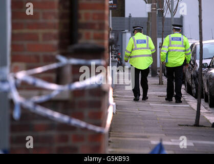 Police community support officers conduct door to door enquires at the scene in Hazlebury Road, Fulham, south west London, where the body of a 73-year-old man was discovered after a violent attack. Stock Photo