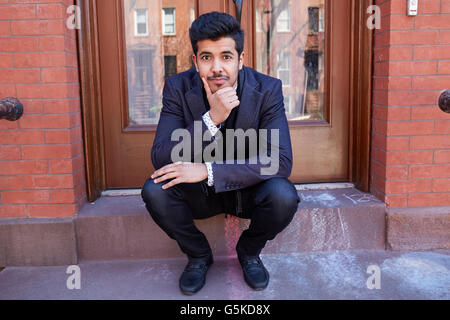 Middle Eastern man sitting on front stoop Stock Photo
