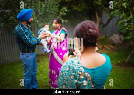 Woman photographing family with cell phone Stock Photo