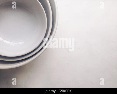 Three white bowls on white textured surface Stock Photo