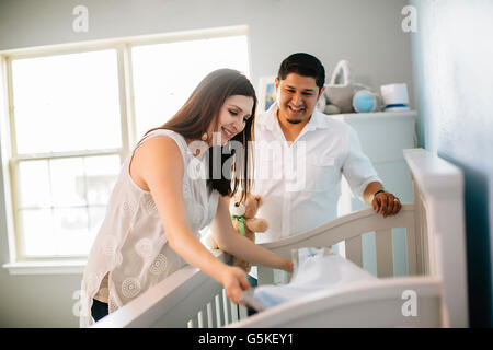 Hispanic couple preparing crib bed in nursery Stock Photo