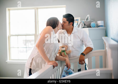 Hispanic couple kissing in nursery Stock Photo