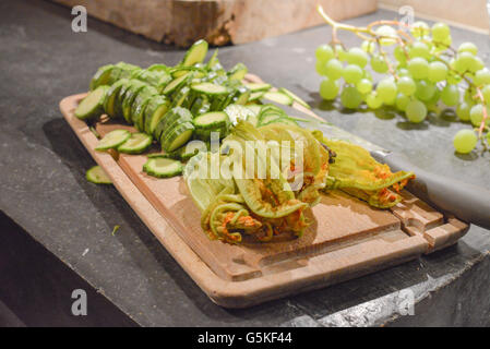 Wood board with fresh sliced zucchini and zucchini flowers. Stock Photo