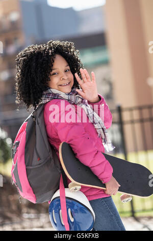 African American girl carrying skateboard outdoors Stock Photo