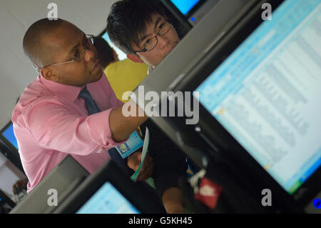 Schoolboy in computer lab with teacher helping Stock Photo - Alamy