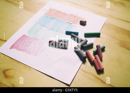 Photograph of a sheet of paper and color chalks in a retro style on a wood table Stock Photo
