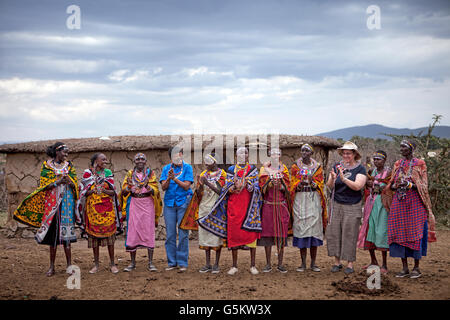 Group of Masai women and two tourists doing a ceremonial dance in a Masai village, Kenya, Africa. Stock Photo