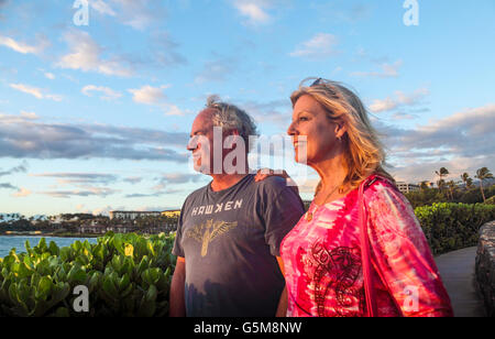 Golden light on tourists enjoying coastal walkway in Wailea, Maui, at sunset Stock Photo