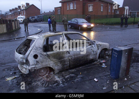 A burnt out car, hijacked in riots last night on the Crumlin Road, stand at the side of the street after two nights of Loyalist and Nationalist rioting in the area. At the Holy Cross School this morning, Protestant residents kept their pledge not to stage any demonstrations. *... against the pupils and their parents as they made their way to the school gates. Stock Photo