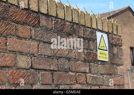 High Wall with Warning Sign and Security Spikes Stock Photo
