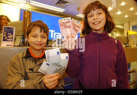 WIlliam Sharpley, eight, from Oxford, and his sister Holly, 11, hold the new Euro notes they purchased at a Travelex bureau-de-change at London's Heathrow airport before boarding a flight to Rome. * Over 300 million residents in European countries woke up to using the new currency. Britain, Denmark and Sweden have not joined the new currency, but several major retailers have said that they will accept it from customers. Stock Photo