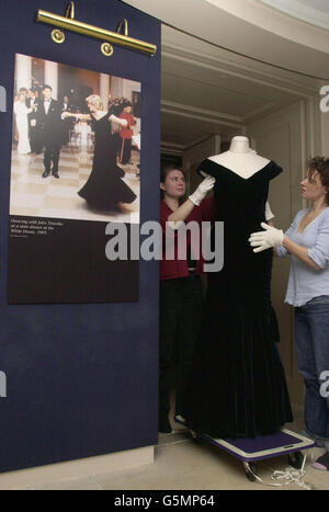 The 1985 Victor Edelstein ink blue silk velvet dress, worn by Princess of Wales in the same year at the White House where she famously danced with American Actor John Travolta (seen in the photograph on the left). *..., is put into position by Textile Conservators Anne-Marie Britton and Lara Flecker (right) inside Kensington Palace, London. The dress is one of many which from this Saturday will form a permanent collection within the Royal Ceremonial Dress Collection inside Kensington Palace and follows a series of temporary exhibitions which began in 1998. Stock Photo