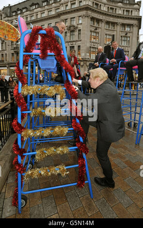 Boris Johnson the Mayor of London climbs up a high chair at Oxford Circus, with West End retailers to promote the Shop West End day, when Oxford Street and Regent Street will be closed to all traffic, on Saturday 24th November, to help Christmas shoppers in central London. Stock Photo