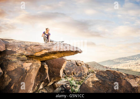 Caucasian woman stretching on rock formation Stock Photo