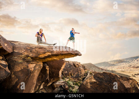 Caucasian couple stretching on rock formation Stock Photo