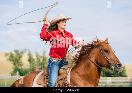Caucasian cowgirl throwing lasso on horseback