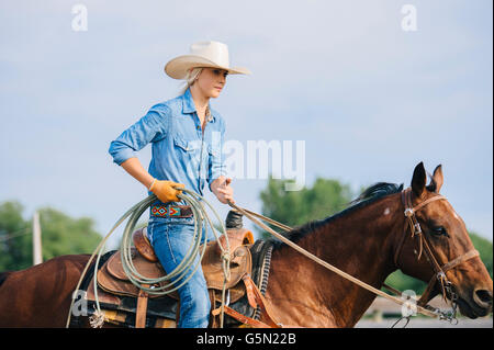 Caucasian cowgirl holding lasso on horseback Stock Photo