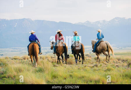 Cowboy and cowgirls riding horseback on ranch Stock Photo