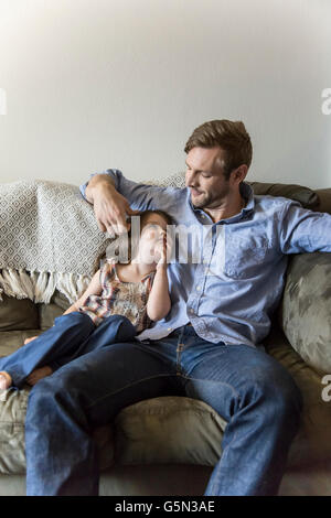 Father and daughter sitting on sofa Stock Photo