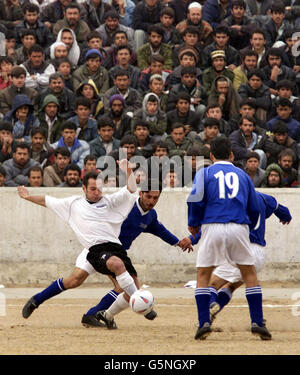Recropped version ...Action from a soccer match at the Olympic Stadium in Kabul, Afghanistan between ISAF (the International Security Assistance Force) and Kabul FC (in blue). The game was organised by the Football Association, * the MoD and Barclaycard the new sponsors the Premiership. Lawrie McMenemy and former Tottenham Hotspurs player Gary Mabbutt have spent two days in the war torn country coaching both teams. The ISAF side includes soldiers from Great Britain, Italy, Germany and Holland and played in the Olympic Stadium more infamous for the executions held there by the former Taliban Stock Photo