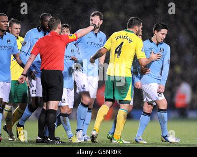 Soccer - Barclays Premier League - Norwich City v Manchester City - Carrow Road. Match referee Mike Jones (left) orders the players away after sending off Manchester City's Samir Nasri (right) Stock Photo